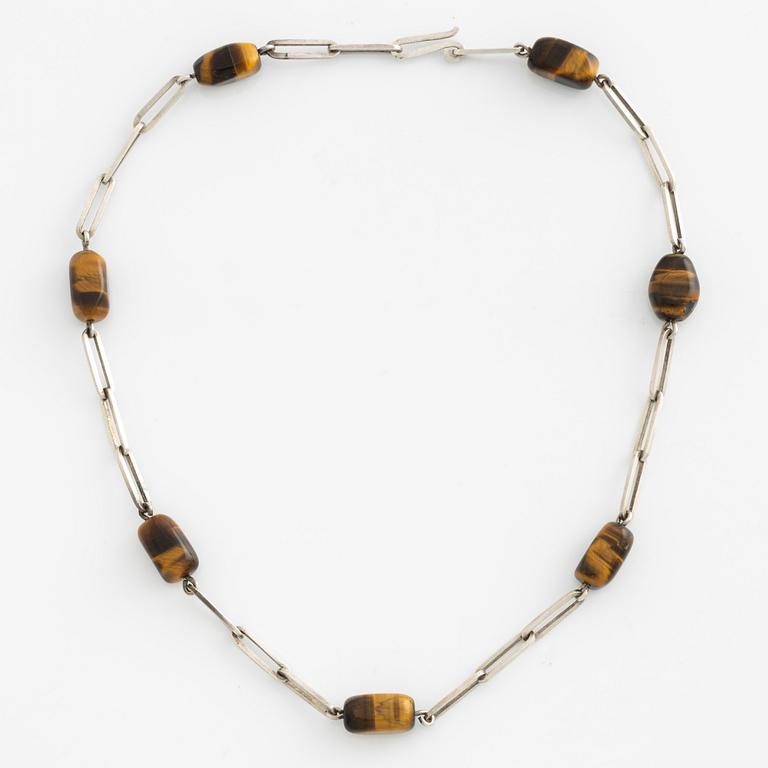 Birger Haglund, a silver and tiger's eye necklace.