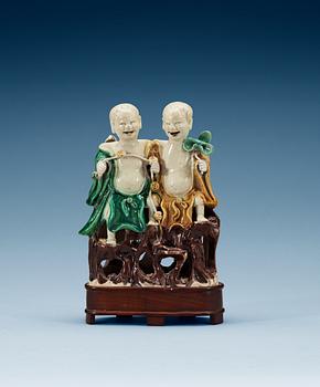 A green, yellow and brown glazed biscuit figure of Laughing boys, Qing dynasty, Kangxi (1662-1722).