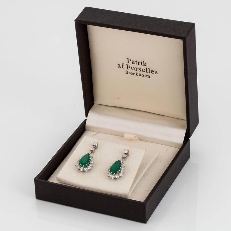 Ett par örhängen med droppformade fasettslipade smaragder samt runda briljantslipade diamanter.