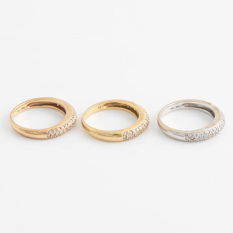 Three 18K gold rings with round brilliant-cut diamonds.