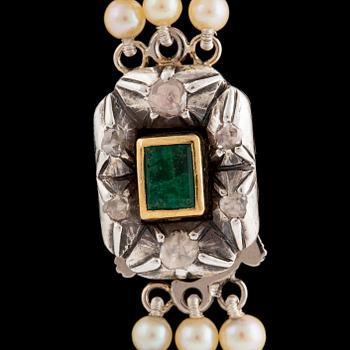 A three strand calibrated pearl necklace, clasp with emerald and diamonds.