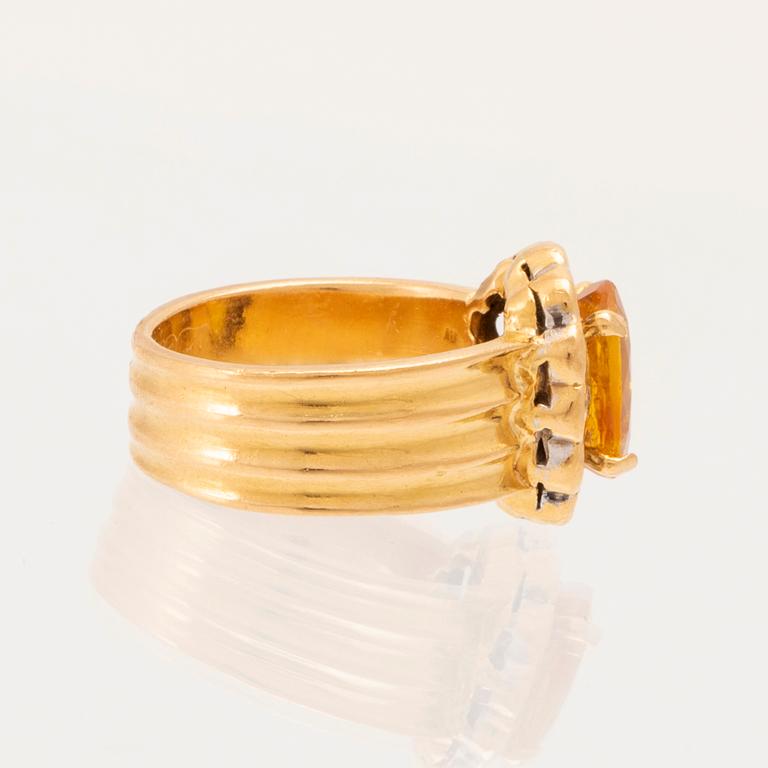 A 22K gold carmosé ring with an oval faceted yellow sapphire and round brilliant-cut diamonds.
