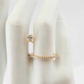 An 18K gold ring set with an oval cut and round brilliant cut diamonds by LWL Jewelry.