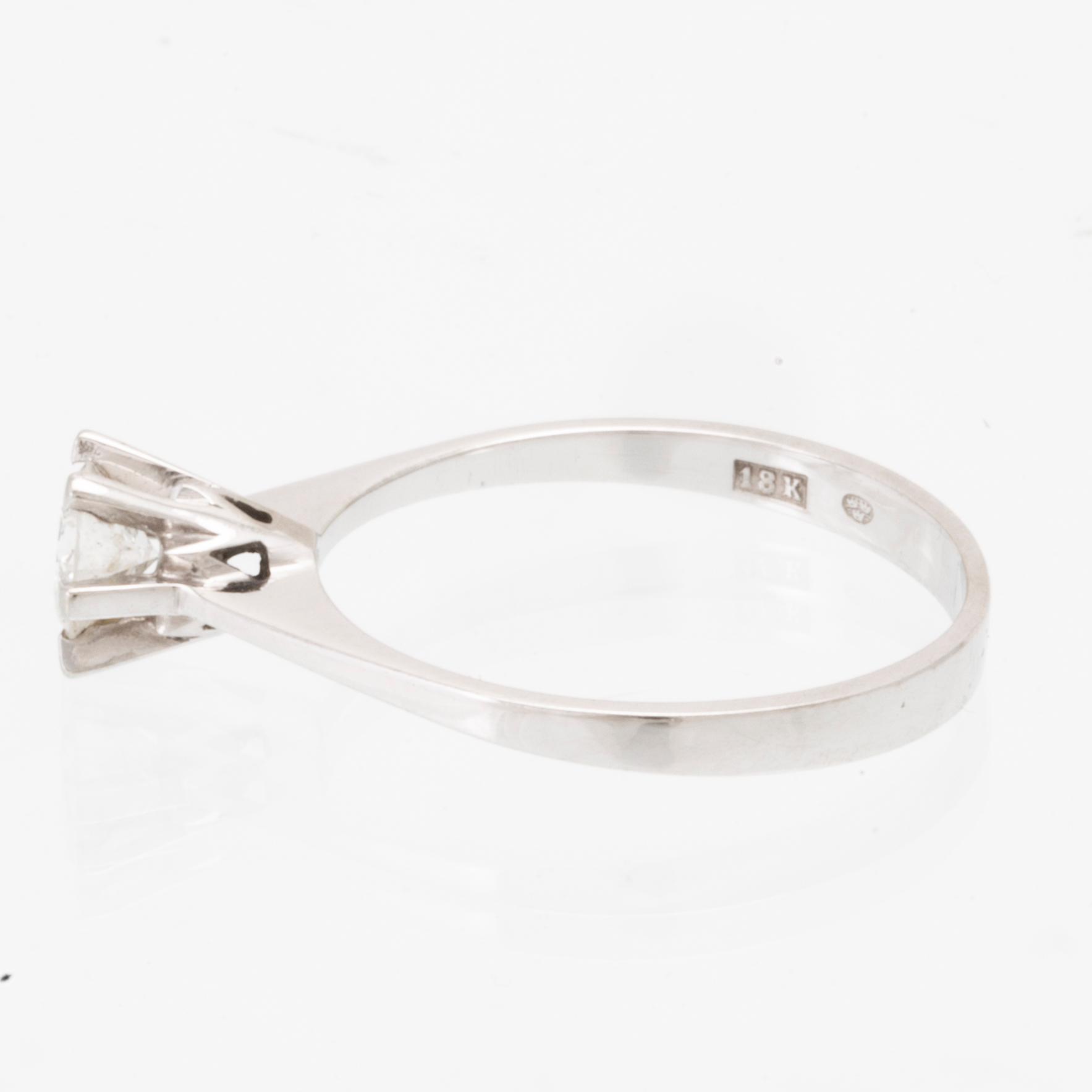 An 18K white gold solitaire ring set with a round brilliant-cut diamond.