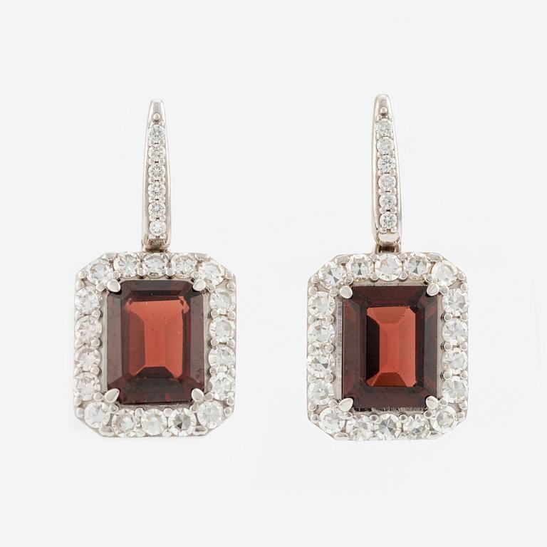 A pair of earrings in 18K white gold with faceted garnets and round brilliant-cut diamonds.