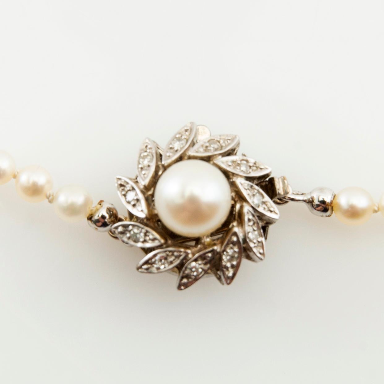Necklace of cultured pearls and a clasp of 18K white gold set with round brilliant-cut diamonds and a cultured pearl.