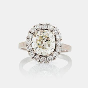 1170. A cushion-cut diamond, circa 3.07 ct ring. The center diamond is surrounded by pavé set brilliant-cut diamonds.