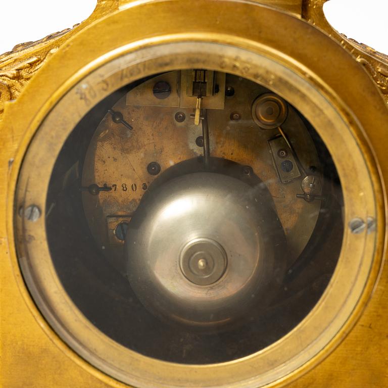 A mantle clock and a pair of candelabra, Louis XVI style, ca 1900.