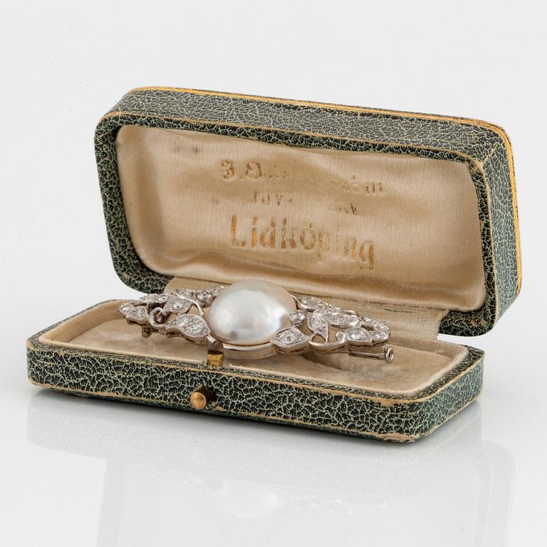 A platinum brooch set with a pearl and old- and rose-cut diamonds.