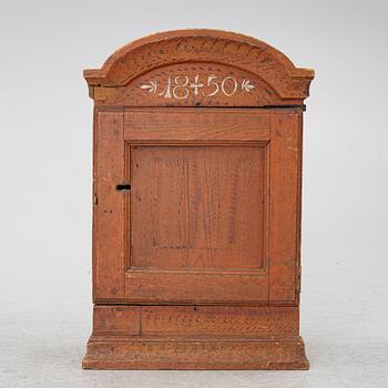 A hanging cabinet, dated 1850.