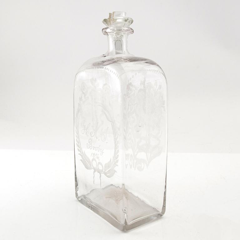 Brännvinsflaska, glas. Daterad Broby 1856.
