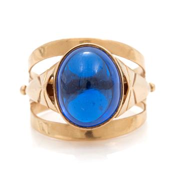 A ring set with an oval, cabochon-cut, synthetic, blue spinel.