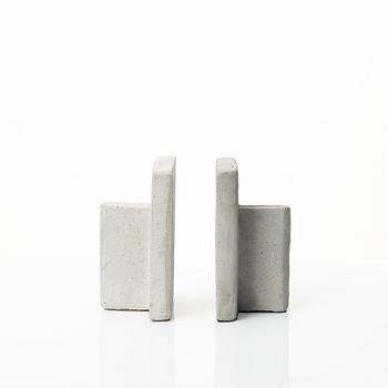 A mixed lot comprising a pair of limestone bookends, a bookshelf and two plates in concrete.