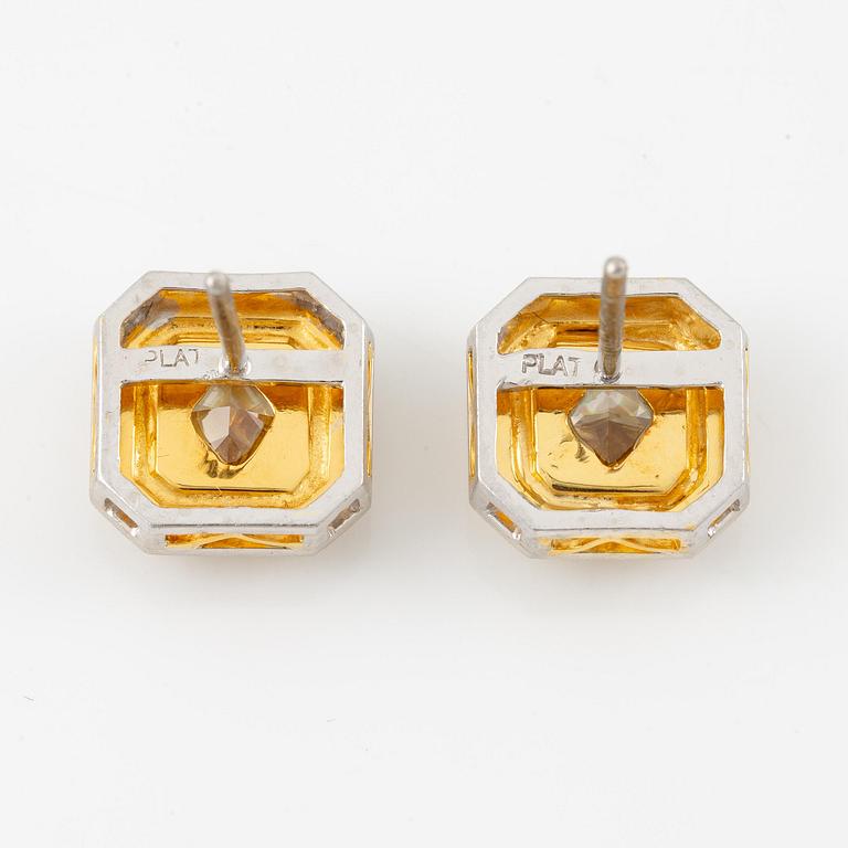 A pair of platinum and gold earrings with two radiant-cut yellow diamonds.