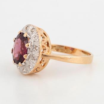 A 14K gold ring set with a garnet and eight-cut diamonds.