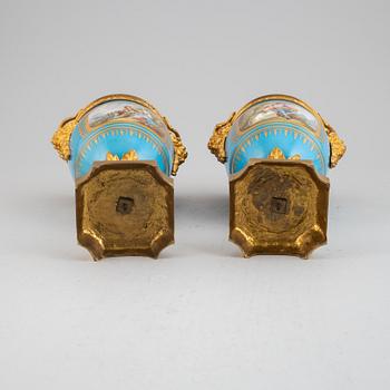 A pair of pordelain and gilt brass urns in teh style of Sevres, 20th Century.