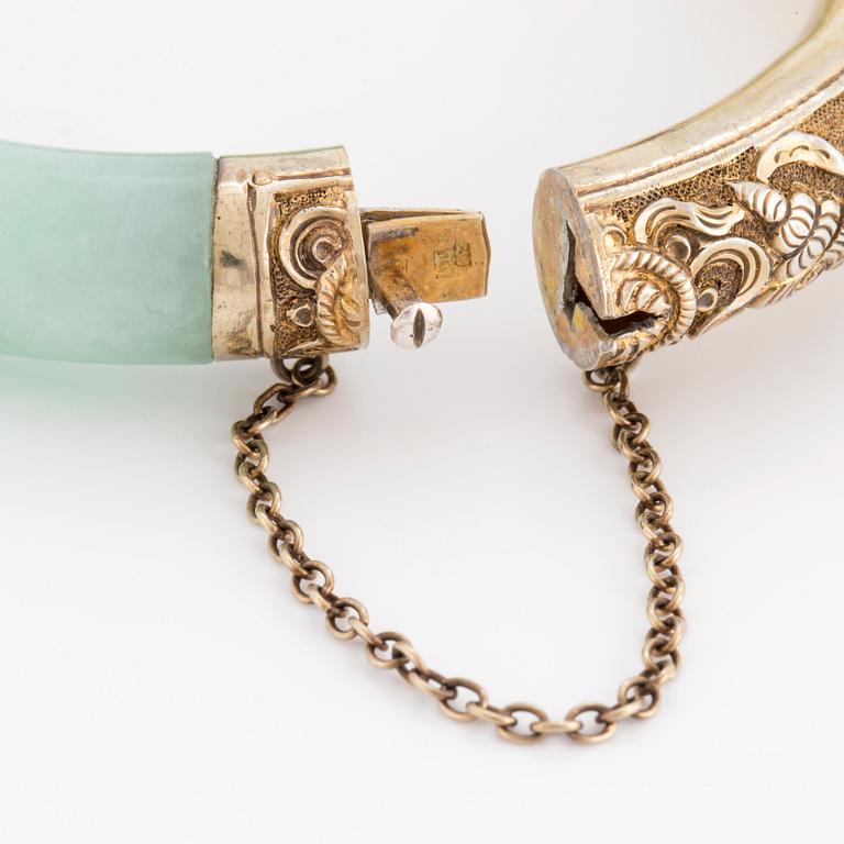 A jade bangle with a gilded silver clasp.