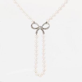 A cultured pearl necklace with a 14K white gold bow pendant set with round brillliant-cut diamonds.