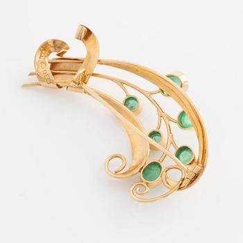 Brooch in 18K gold set with cabochon-cut emeralds.