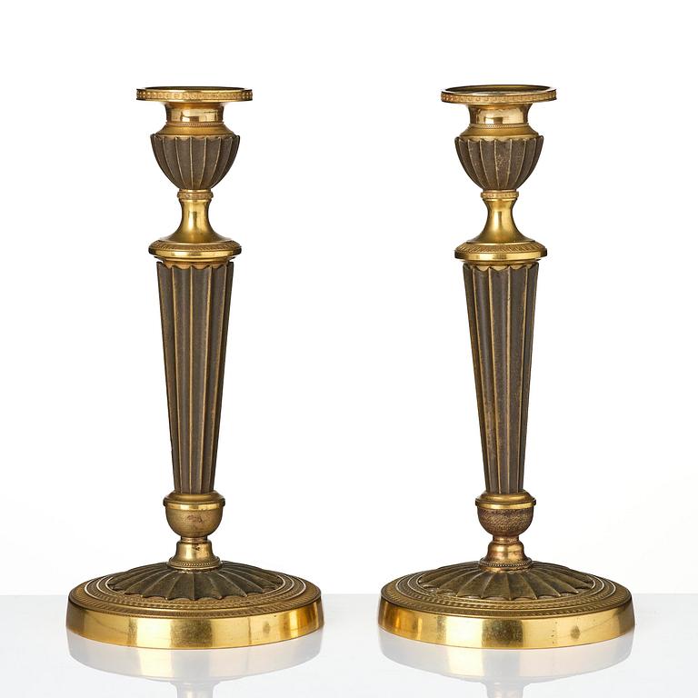 A pair of French Empire patinated and ormolu candlesticks, early 19th century.