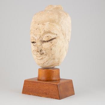 A South East Asian stone mass sculpture of a head, presumably modern manufacturing.