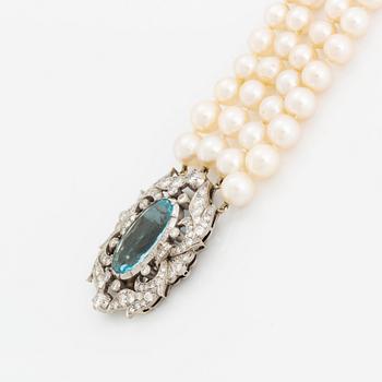 A four strand cultured pearl necklace with a clasp in 14K gold set with a faceted aquamarine.