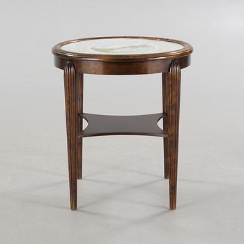 A table from the first halft of the 20th century with a "Kalmar Fajans" tabletop, painted by John Sjöstrand.