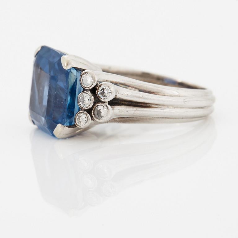 An 18K white gold ring set with a faceted sapphire and round brilliant-cut diamonds.