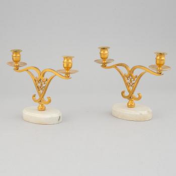 A pair of brass candle sticks om marble stands from the middle of 20th century.