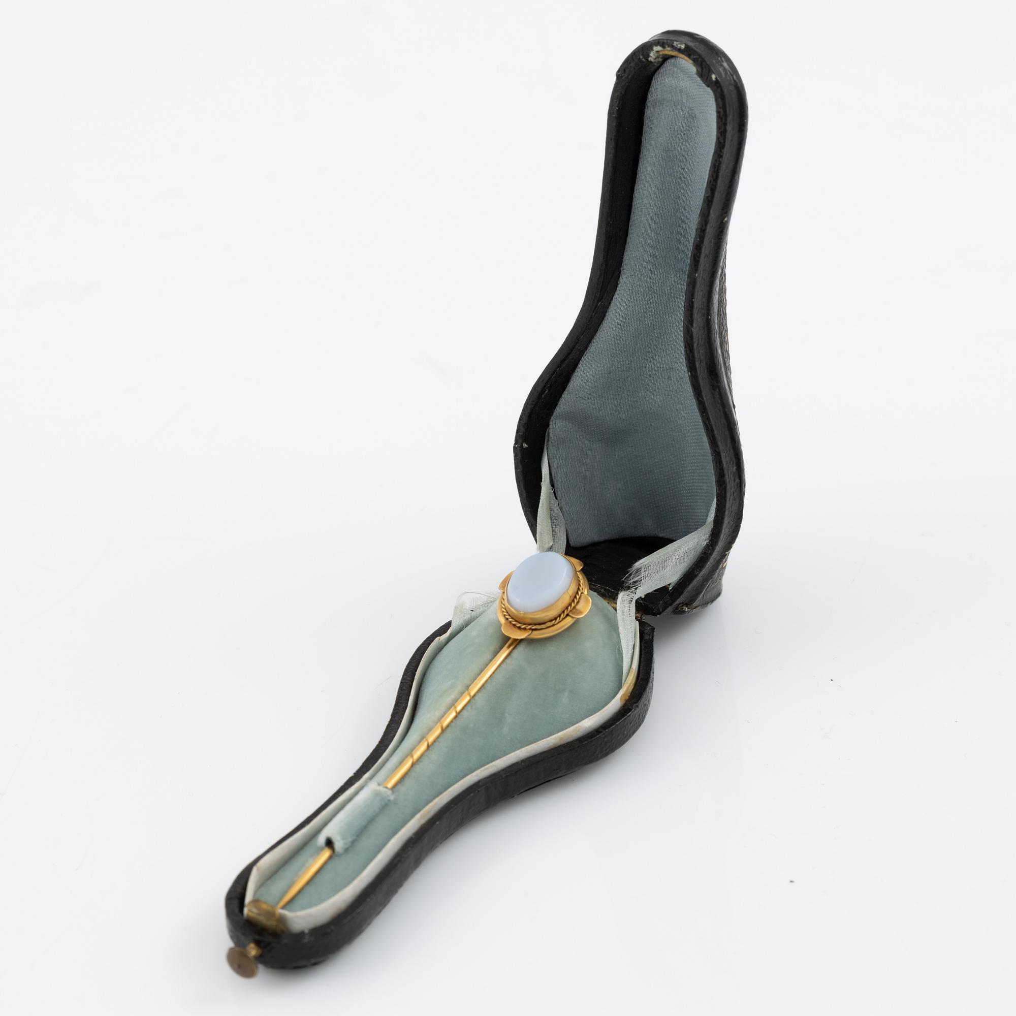 Brooch pin of low-grade gold with a white-blue stone.