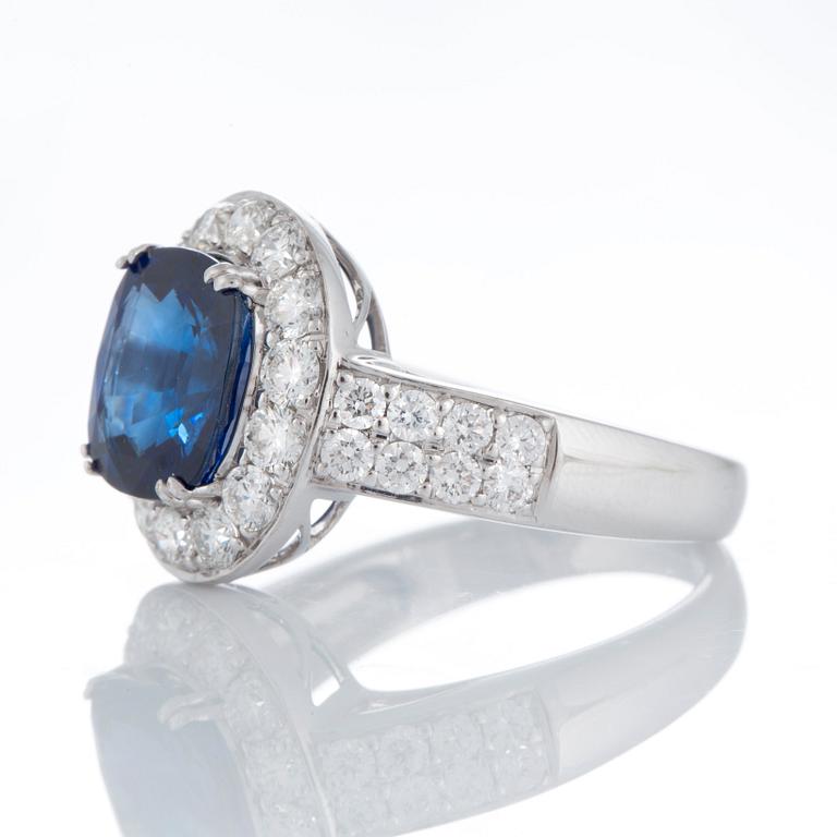 A ring set with a faceted sapphire 4.99 cts according to information given and round brillliant-cut diamonds.