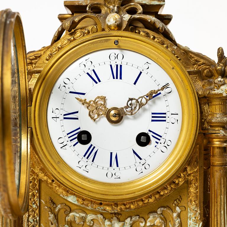 A mantle clock and a pair of candelabra, Louis XVI style, ca 1900.