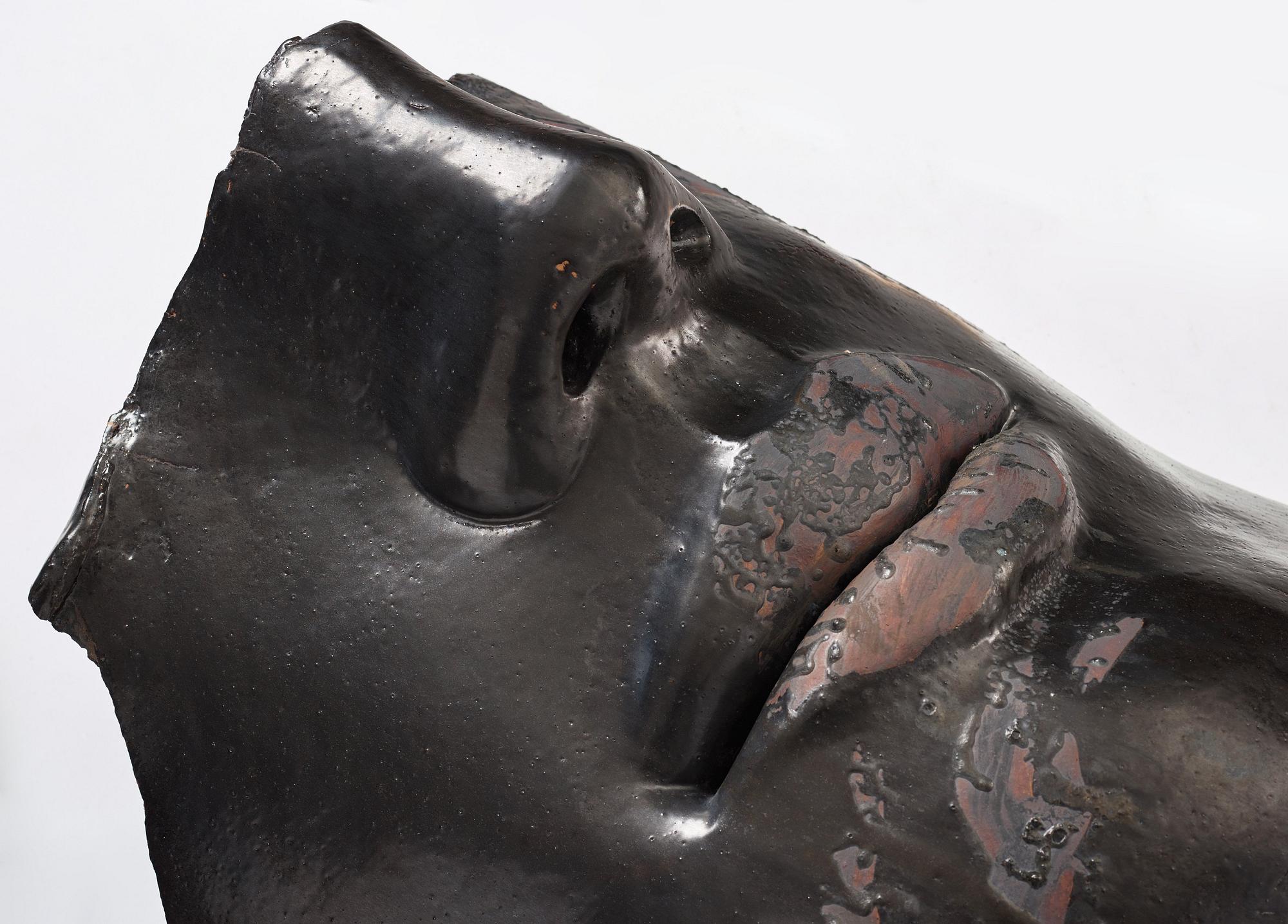 Hertha Hillfon, a black glazed stoneware wall sculpture in two parts of a face and a sky, executed in her own studio, Stockholm 1960s.