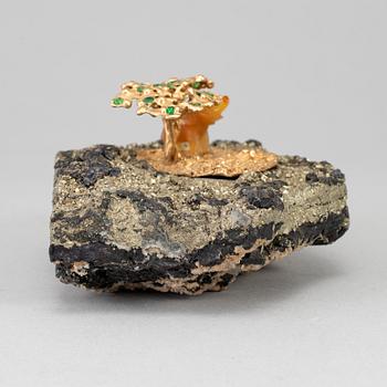 A sculpture of an agate elephant under a gilt three with inlays of tsavorites on rock formation, unmarked, 20th Century.