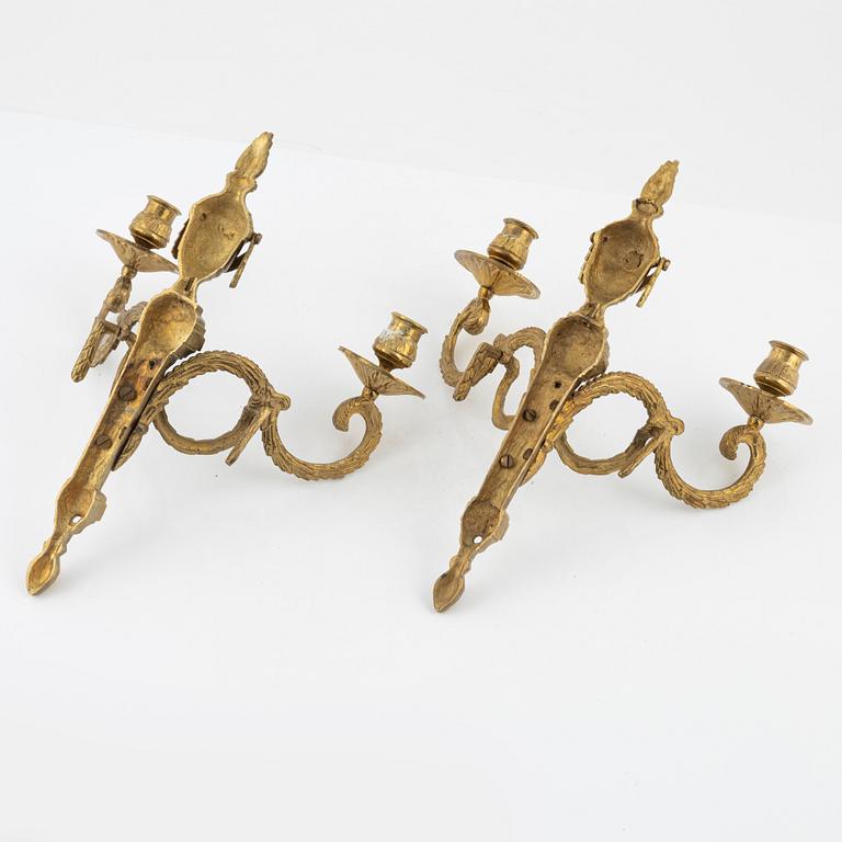 A pair of brass Louis XVI-style two-light wall lights, early 20th Century.