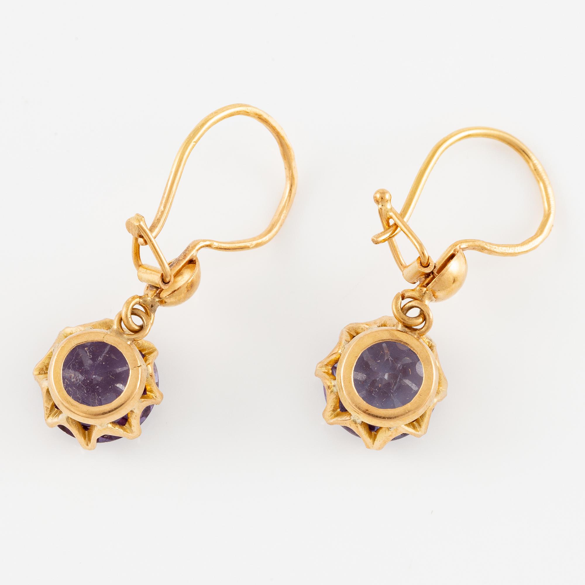 A pair of earrings in 18K gold with purple stones.