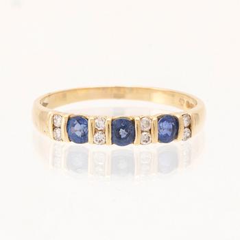 An 18K gold ring set with round brilliant-cut diamonds and round faceted blue stones, London England.