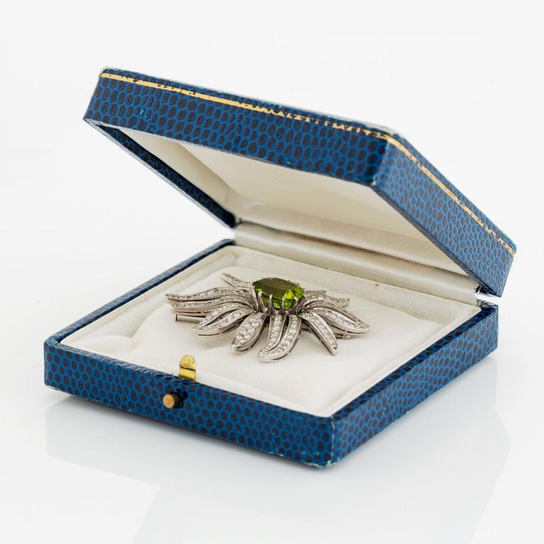 An 18K white gold brooch set with a faceted peridot and eight-cut diamonds.