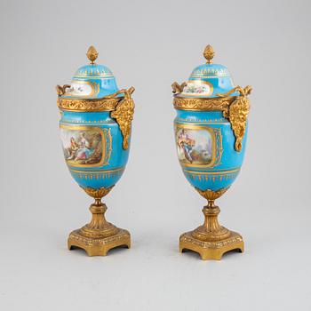 A pair of pordelain and gilt brass urns in teh style of Sevres, 20th Century.