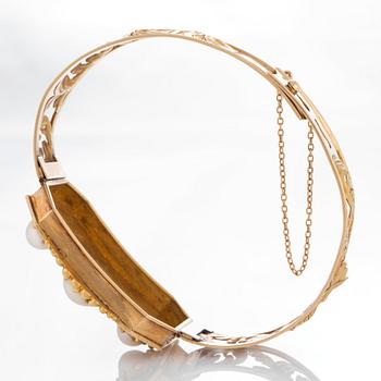 An 18K gold bracelet set with three pearls.