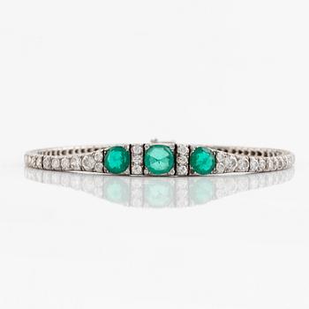 A platinum bracelet set with emeralds and round brilliant-cut diamonds.