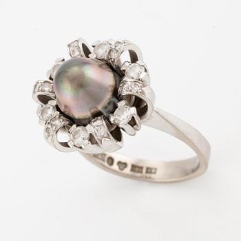 An 18K white gold ring set  with a pearl and round brilliant-cut diamonds.