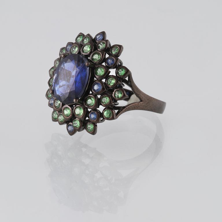 RING, 18K guld med fasettsliapde blå safirer ca 0.18 ct, kyanit ca 2.88 ct samt demantoider ca 0.60 ct. Vikt 6,2 gram.