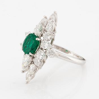 An platinum ring set with a faceted emerald and brilliant-cut pearshaped diamonds.