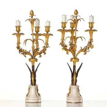 A pair of three-light Louis XVI patinated and ormolu candelabra in the manner of François Rémond, late 18th century.