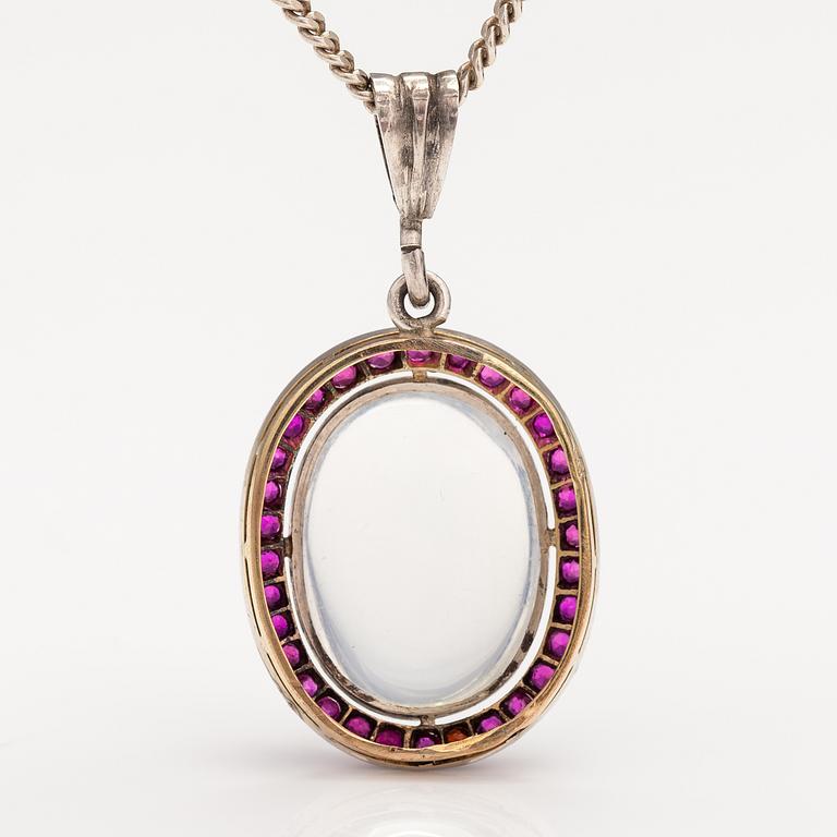 A 14K gold and silver necklace with a moon stone, rubies and a red glass stone.