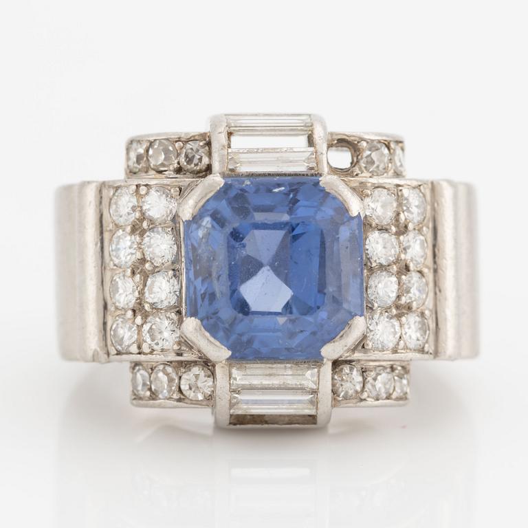 A platinum ring with a faceted sapphire and round brilliant-, eight-, and baguette-cut diamonds.