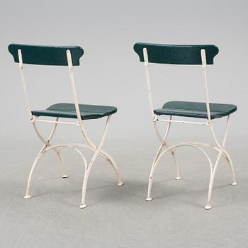 A pair of cast iron chais with wooden seats and a cast iron table, early 20th century.