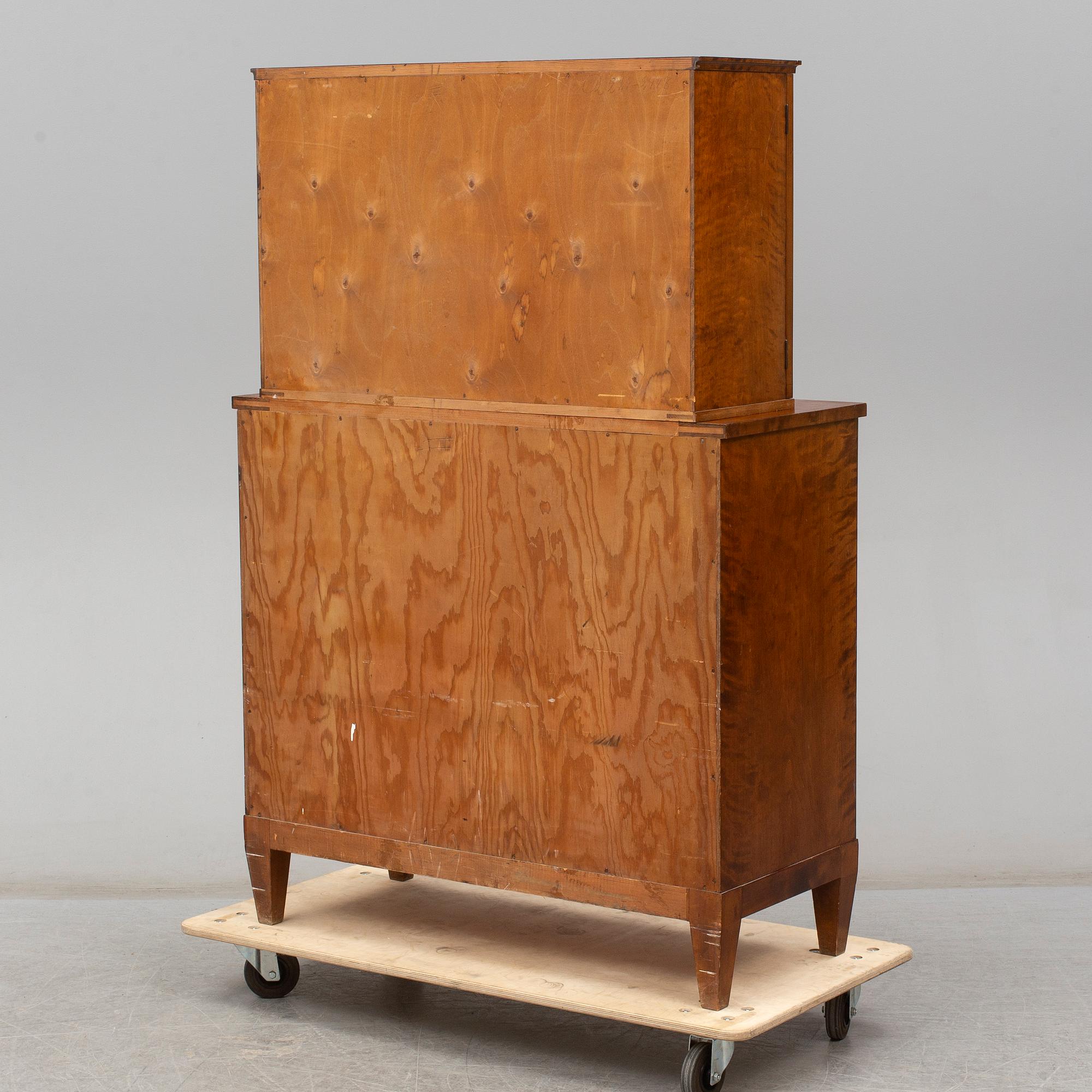 a chest of drawers with a vitrine cabinet from the early 20th century.