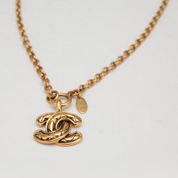 CHANEL, a gold colored chain with CC pendant.